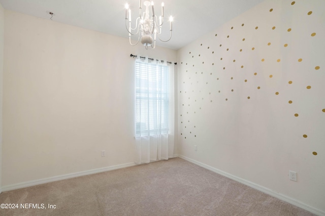 carpeted empty room featuring a chandelier