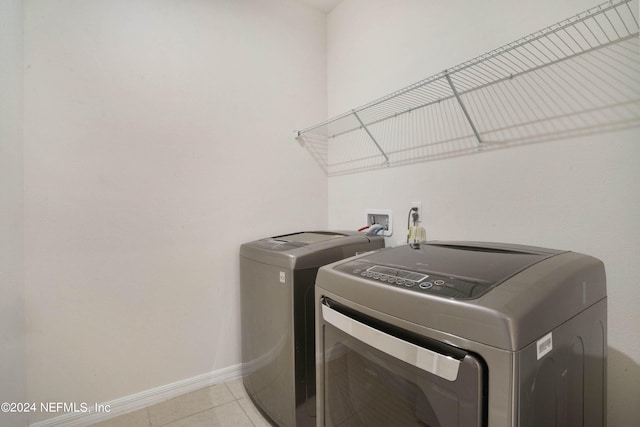 clothes washing area with washer hookup, washer and clothes dryer, and light tile flooring