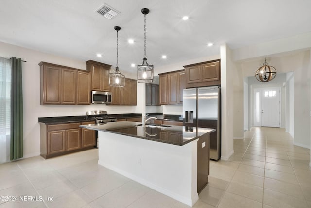 kitchen featuring a center island with sink, hanging light fixtures, light tile floors, and stainless steel appliances