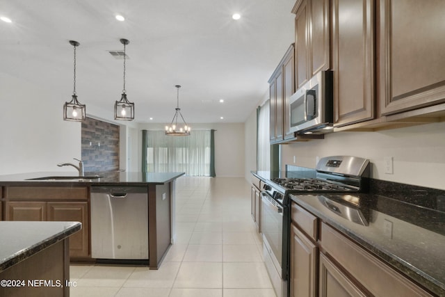 kitchen with decorative light fixtures, sink, stainless steel appliances, dark stone countertops, and a chandelier