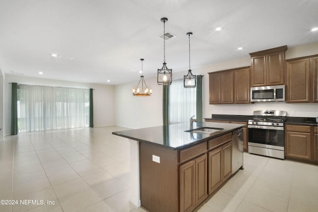 kitchen featuring appliances with stainless steel finishes, a chandelier, a center island with sink, sink, and hanging light fixtures