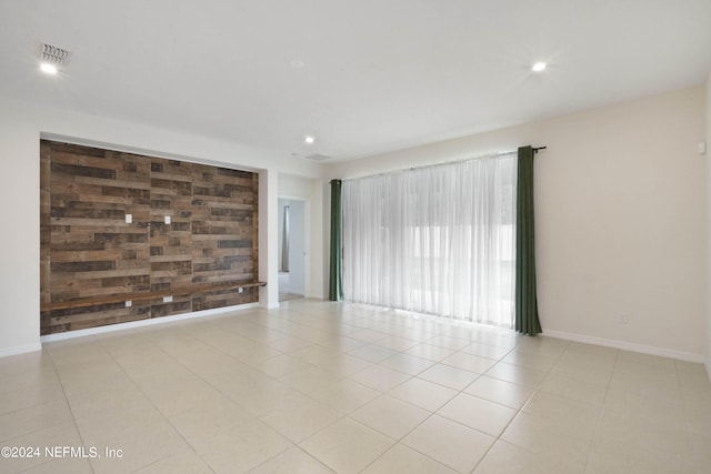 spare room featuring wooden walls and light tile floors