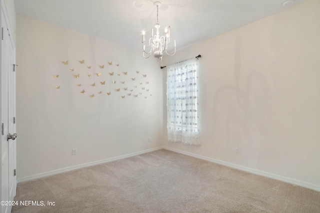 empty room featuring light carpet and a notable chandelier