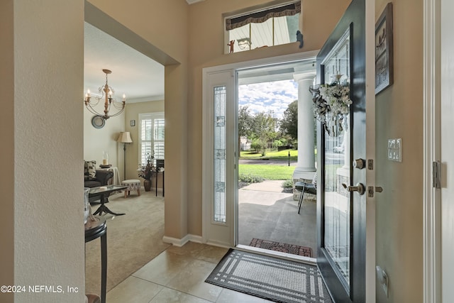 entrance foyer with light carpet, an inviting chandelier, ornamental molding, and a wealth of natural light