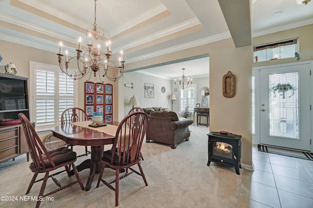 dining space featuring crown molding, an inviting chandelier, a tray ceiling, and a wood stove