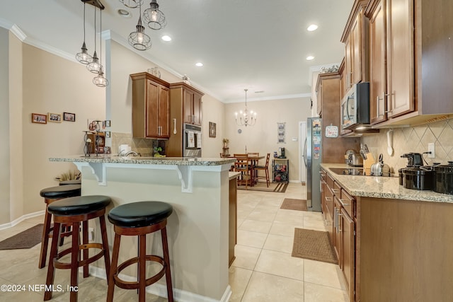 kitchen featuring pendant lighting, appliances with stainless steel finishes, backsplash, a breakfast bar area, and a notable chandelier