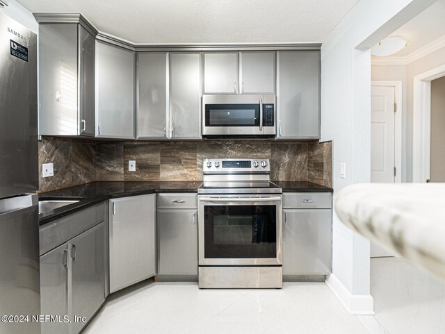 1530 El Prado Rd Unit 5, Jacksonville, FL 32216 - kitchen with gray cabinetry, tasteful backsplash, stainless steel appliances, and light tile floors