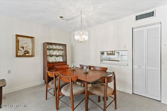 dining room featuring a notable chandelier, a textured ceiling, and light colored carpet