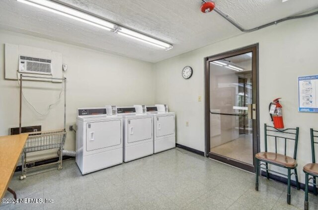 laundry area with washing machine and clothes dryer, a textured ceiling, light tile patterned floors, and a wall mounted AC