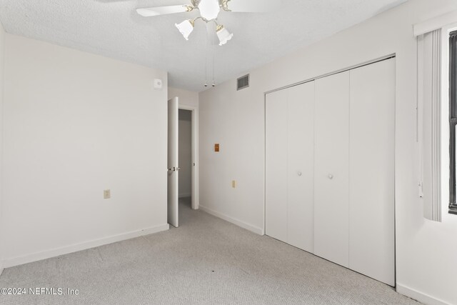 unfurnished bedroom with ceiling fan, a closet, and light colored carpet