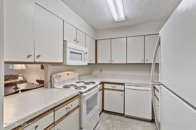 kitchen featuring white appliances, white cabinets, a textured ceiling, and light tile patterned floors