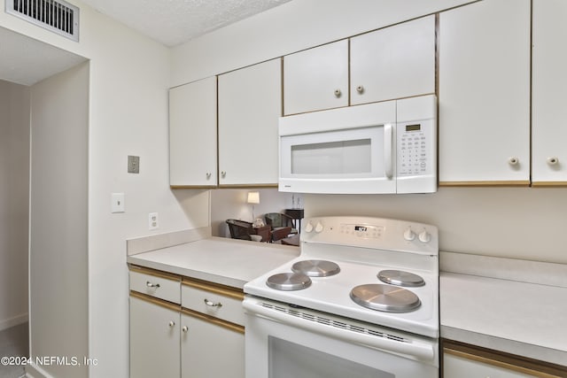 kitchen with white cabinetry, a textured ceiling, and white appliances