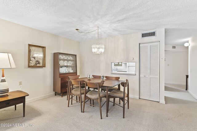 dining space with a chandelier, light colored carpet, and a textured ceiling