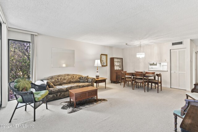 carpeted living room featuring a notable chandelier and a textured ceiling