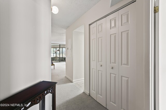 hallway featuring a textured ceiling and light colored carpet