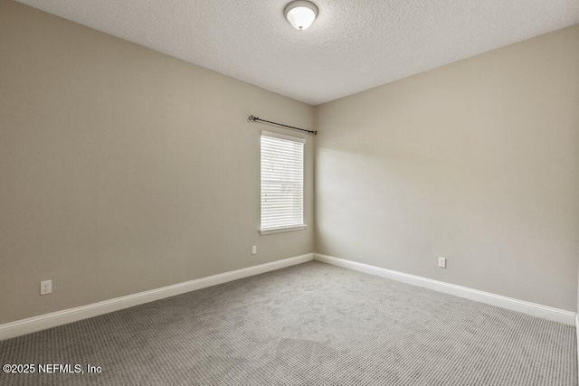 spare room with carpet floors, a textured ceiling, and baseboards