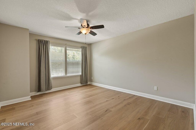 empty room featuring a textured ceiling, baseboards, a ceiling fan, and light wood-style flooring