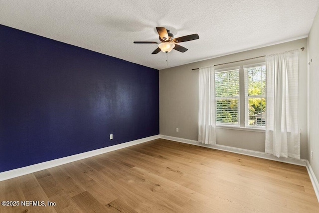 spare room featuring baseboards, a ceiling fan, a textured ceiling, and wood finished floors