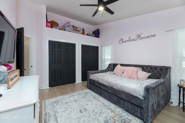 bedroom featuring two closets, ceiling fan, and light hardwood / wood-style flooring