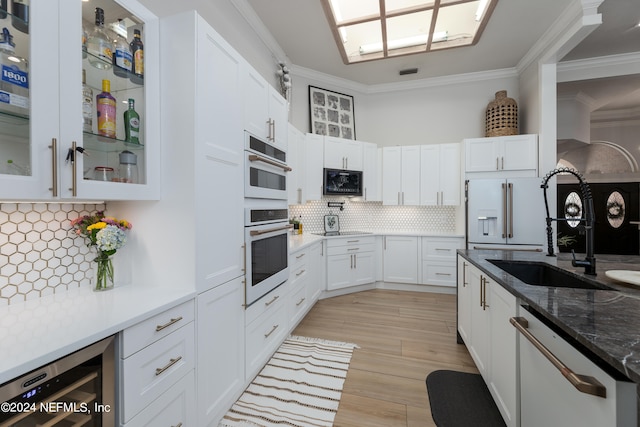 kitchen featuring tasteful backsplash, black microwave, high end white refrigerator, ornamental molding, and white cabinets