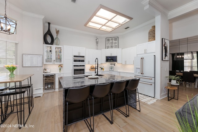 kitchen featuring an inviting chandelier, high end white fridge, white cabinetry, beverage cooler, and a kitchen breakfast bar