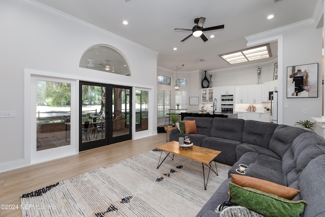 living room with ceiling fan, crown molding, light hardwood / wood-style flooring, and french doors