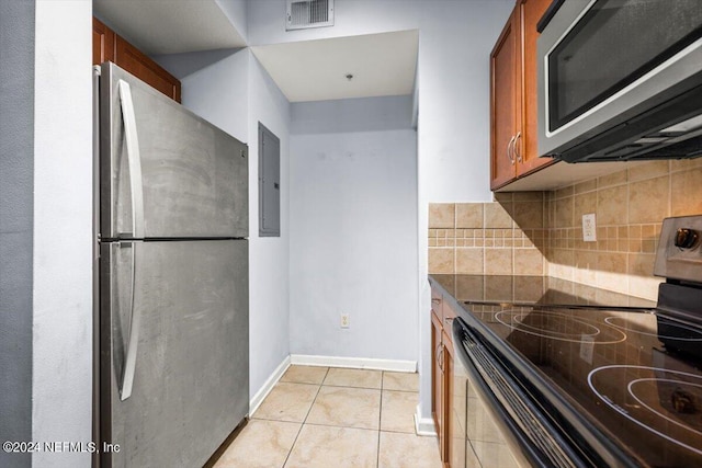 kitchen with light tile patterned flooring, stainless steel appliances, electric panel, and decorative backsplash