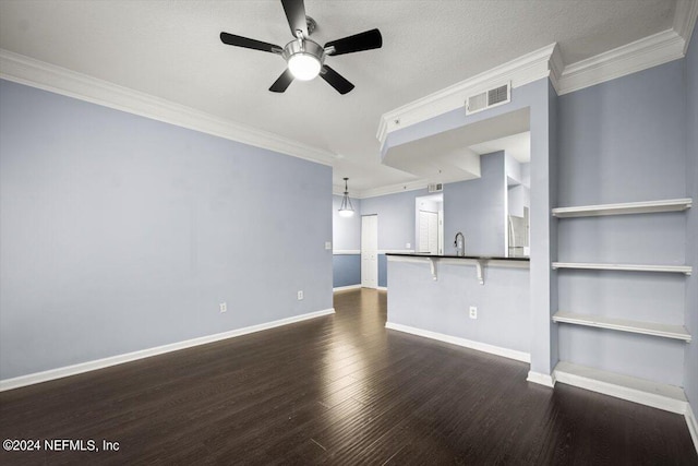 unfurnished living room featuring built in features, dark wood-type flooring, ornamental molding, and ceiling fan