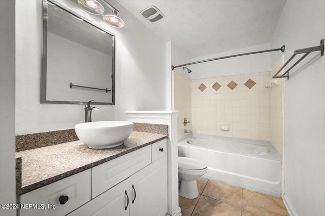 full bathroom with tile patterned floors, toilet, tiled shower / bath, a textured ceiling, and vanity