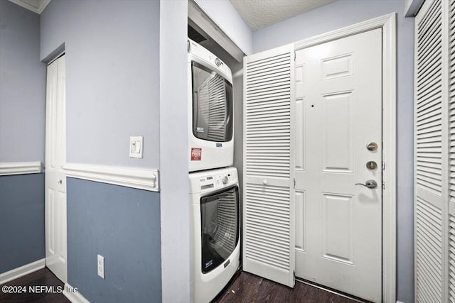 laundry area with dark hardwood / wood-style floors, stacked washing maching and dryer, and a textured ceiling