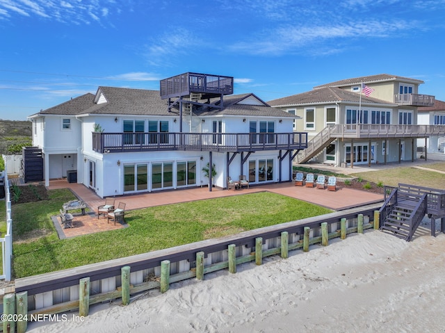 rear view of property featuring a balcony, french doors, a yard, and a patio