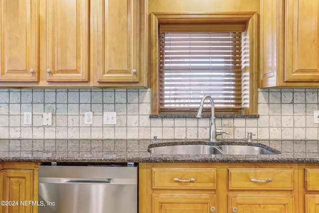 kitchen featuring dark stone counters, backsplash, stainless steel dishwasher, and sink