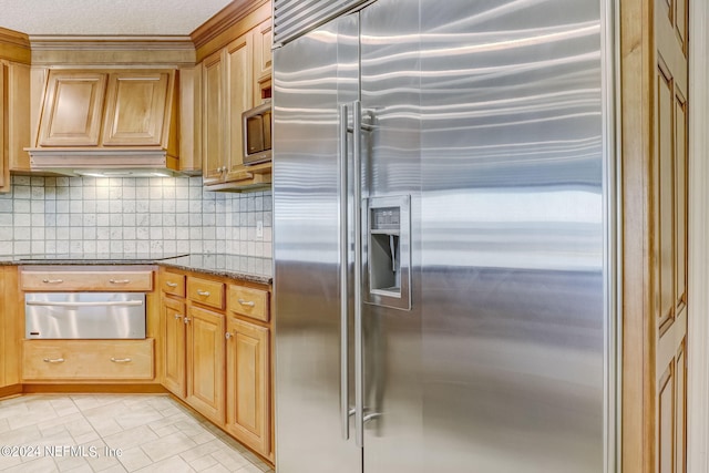 kitchen with premium range hood, built in appliances, light tile floors, backsplash, and dark stone countertops