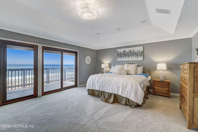 bedroom featuring a tray ceiling, a water view, access to outside, light carpet, and ornamental molding