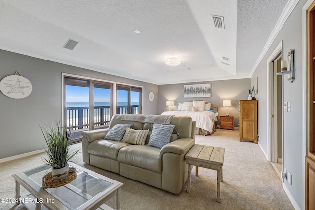 carpeted living room featuring a water view, a tray ceiling, ornamental molding, and a textured ceiling