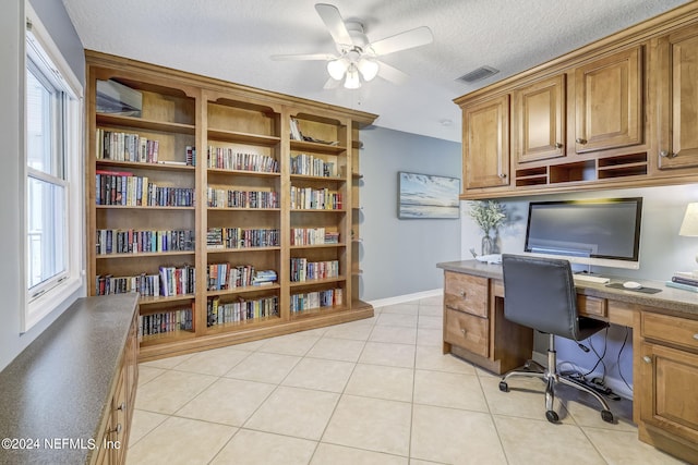 office featuring light tile floors, a textured ceiling, ceiling fan, and built in desk