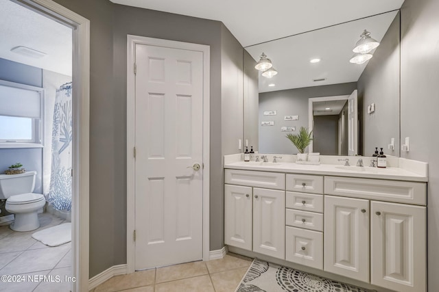 bathroom featuring dual vanity, tile floors, and toilet