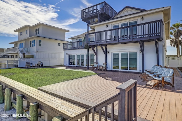 rear view of property featuring a balcony, a deck, and a yard