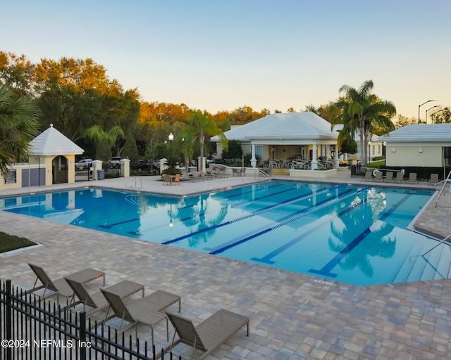 pool at dusk featuring a patio