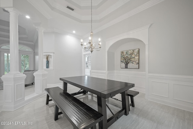 dining space with crown molding, a high ceiling, a chandelier, and decorative columns