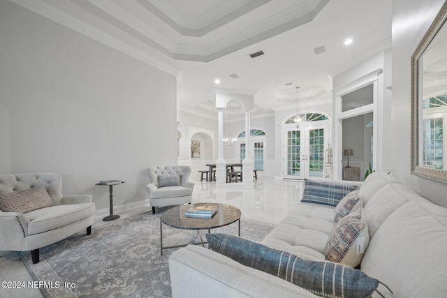 living room featuring french doors, a tray ceiling, a notable chandelier, and ornamental molding