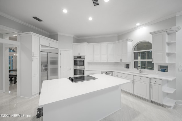 kitchen with appliances with stainless steel finishes, a center island, ornamental molding, sink, and white cabinetry