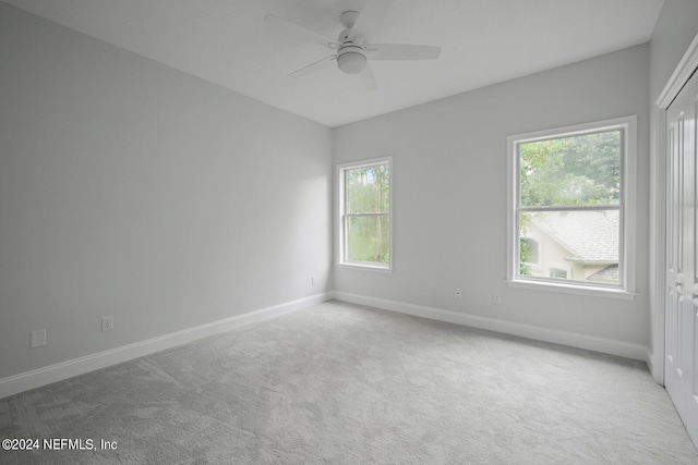 spare room featuring a wealth of natural light, ceiling fan, and carpet