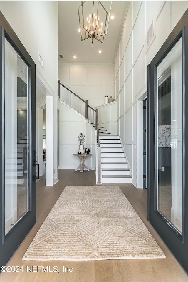 interior space with crown molding, a towering ceiling, and a chandelier