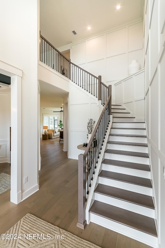 staircase with a towering ceiling and hardwood / wood-style floors