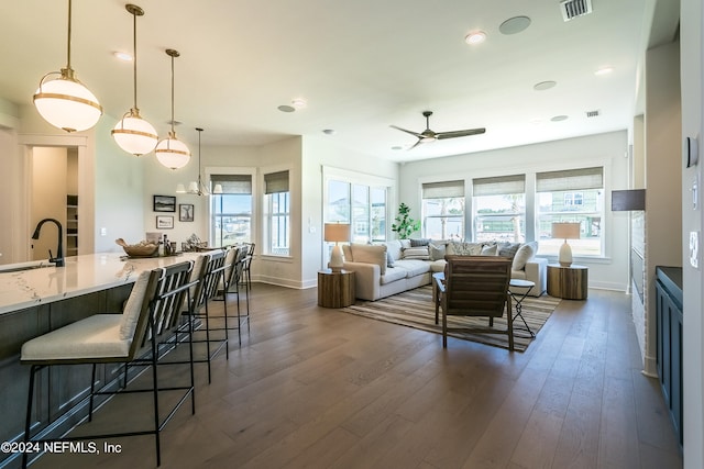 kitchen with dark wood-type flooring, a breakfast bar area, hanging light fixtures, and plenty of natural light