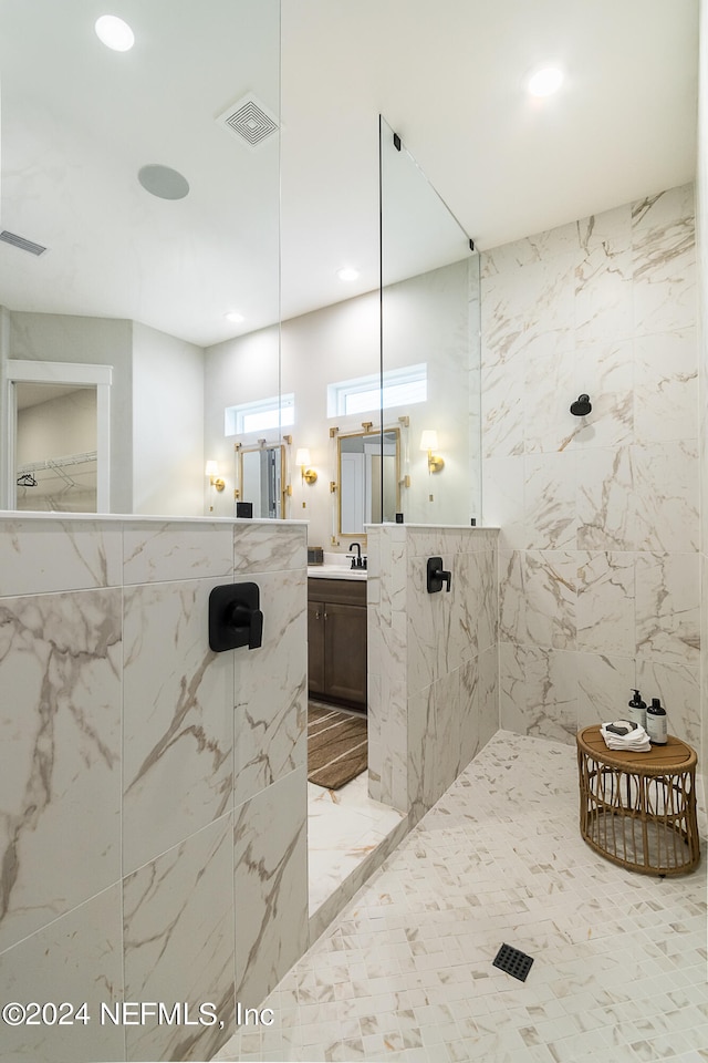 bathroom featuring tile walls, vanity, and a tile shower