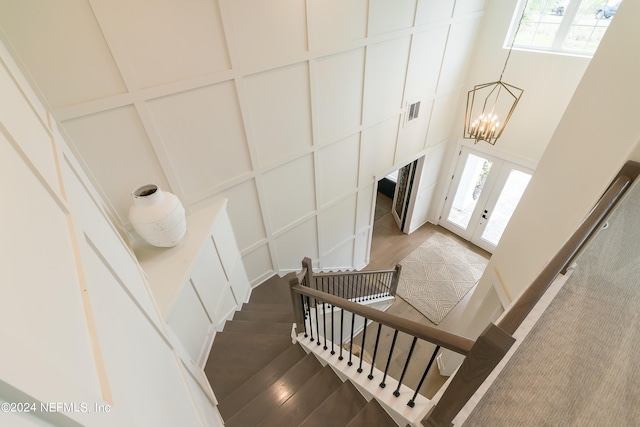 stairway with a high ceiling, wood-type flooring, a wealth of natural light, and french doors