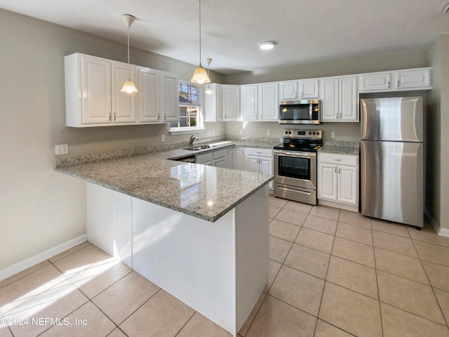 kitchen with light tile floors, appliances with stainless steel finishes, hanging light fixtures, and kitchen peninsula