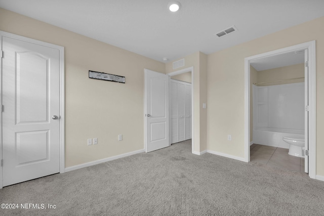 unfurnished bedroom with ensuite bath and light colored carpet